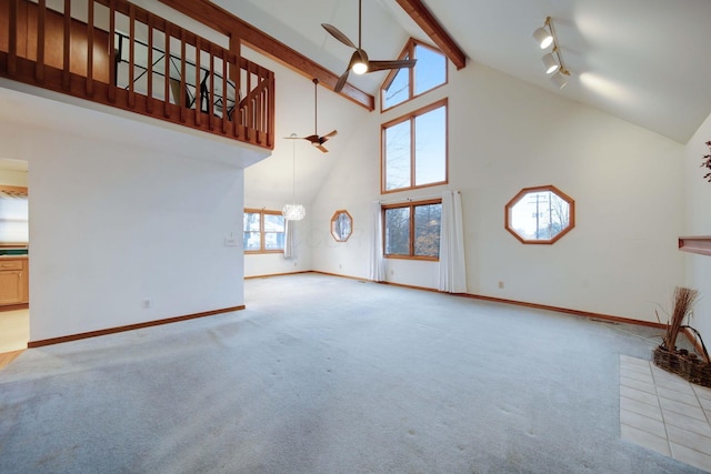 unfurnished living room with rail lighting, beamed ceiling, high vaulted ceiling, light carpet, and ceiling fan with notable chandelier