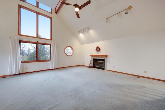 unfurnished living room with ceiling fan, a wealth of natural light, rail lighting, and high vaulted ceiling