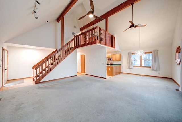 unfurnished living room featuring ceiling fan with notable chandelier, light carpet, and high vaulted ceiling