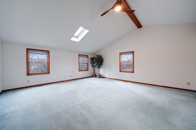 carpeted empty room with ceiling fan and vaulted ceiling with skylight