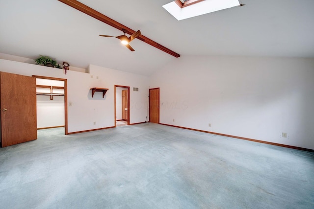 carpeted empty room featuring beamed ceiling, ceiling fan, high vaulted ceiling, and a skylight