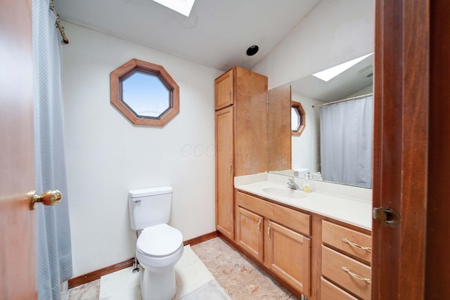 bathroom featuring toilet, vanity, lofted ceiling with skylight, and tile patterned flooring