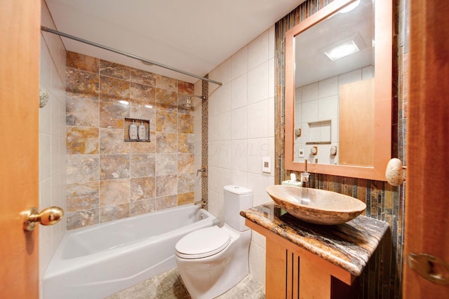 full bathroom with vanity, toilet, tile walls, and tiled shower / bath