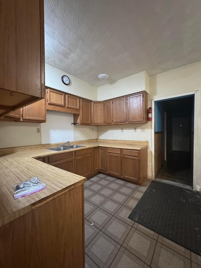 kitchen with a textured ceiling, kitchen peninsula, and sink