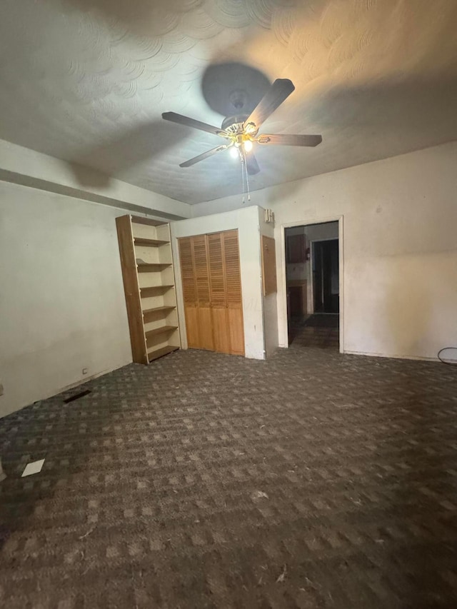 interior space with dark carpet and ceiling fan