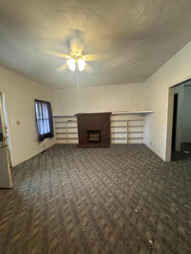 unfurnished living room with dark colored carpet, ceiling fan, and a brick fireplace