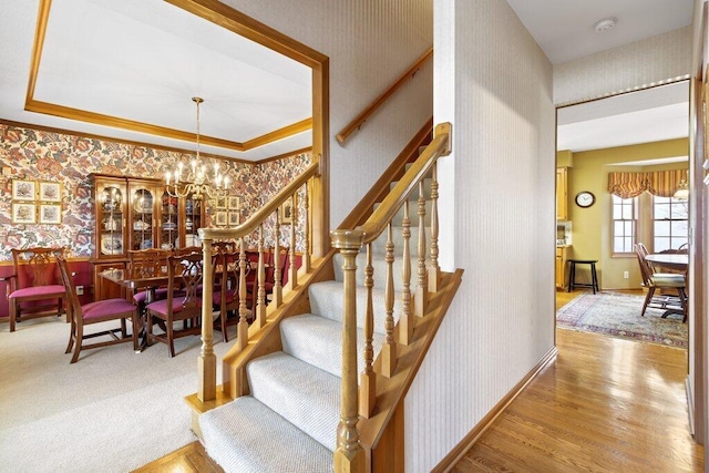 stairway with ornamental molding, a chandelier, and hardwood / wood-style flooring