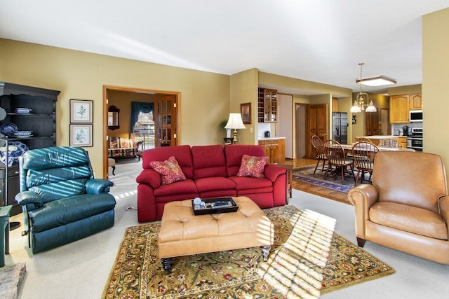 carpeted living room featuring an inviting chandelier