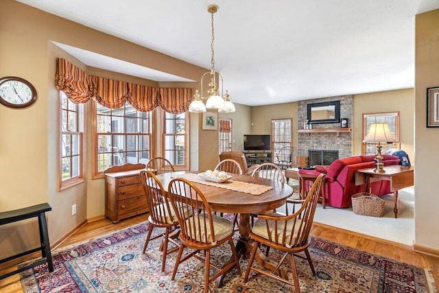 dining space with a fireplace, plenty of natural light, a chandelier, and hardwood / wood-style flooring