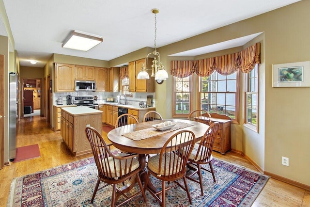 dining space featuring sink, a notable chandelier, and light wood-type flooring