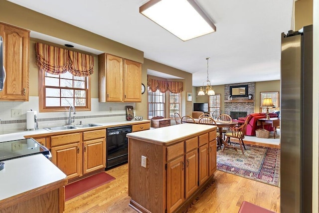 kitchen featuring dishwasher, a kitchen island, tasteful backsplash, sink, and stainless steel fridge