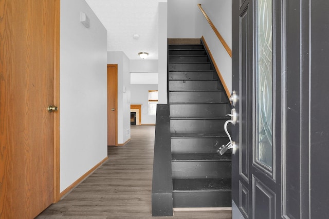 stairway with a fireplace and wood-type flooring