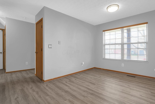 empty room featuring light wood-type flooring and a textured ceiling