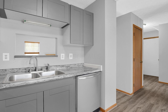 kitchen with a textured ceiling, sink, gray cabinets, dishwasher, and light hardwood / wood-style floors