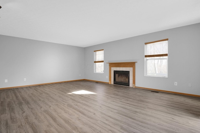 unfurnished living room with a tile fireplace and light hardwood / wood-style flooring