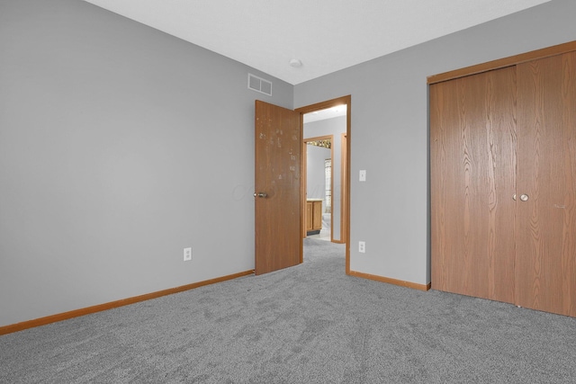 unfurnished bedroom featuring a closet and light colored carpet