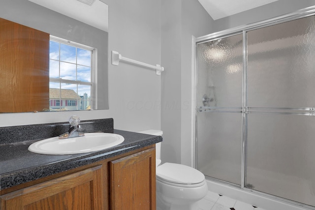 bathroom featuring tile patterned floors, vanity, a shower with shower door, and toilet