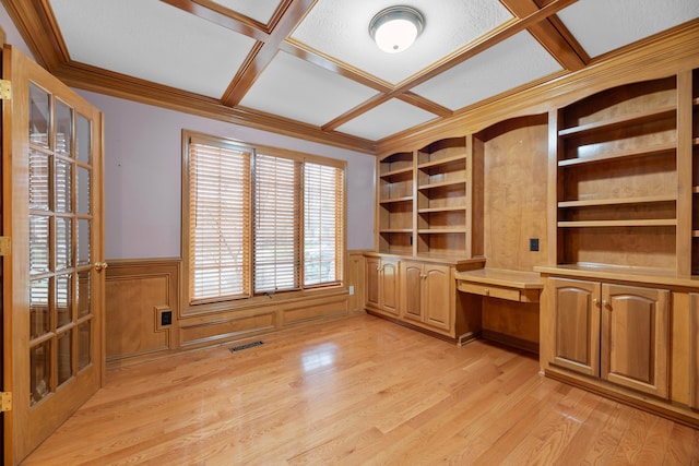 unfurnished office featuring coffered ceiling, a textured ceiling, crown molding, built in desk, and light hardwood / wood-style flooring