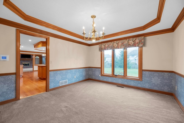 spare room featuring a raised ceiling, crown molding, light carpet, and an inviting chandelier