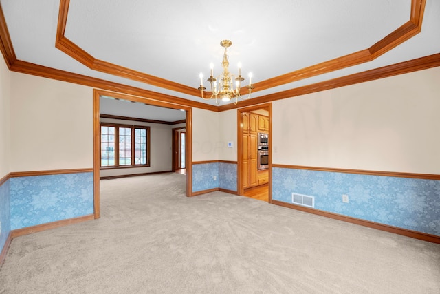 spare room featuring a raised ceiling, ornamental molding, and a chandelier