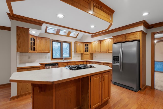 kitchen featuring sink, light wood-type flooring, ornamental molding, a kitchen island, and stainless steel appliances