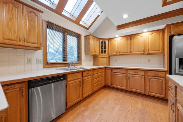 kitchen featuring sink, stainless steel appliances, backsplash, lofted ceiling with skylight, and light wood-type flooring