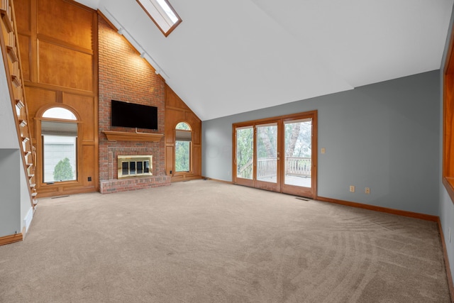 unfurnished living room featuring light carpet, a fireplace, high vaulted ceiling, and a skylight