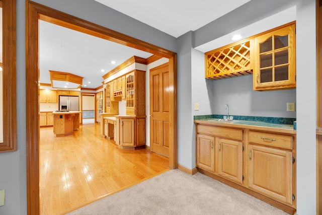 kitchen featuring sink, light hardwood / wood-style floors, stainless steel refrigerator with ice dispenser, and ornamental molding