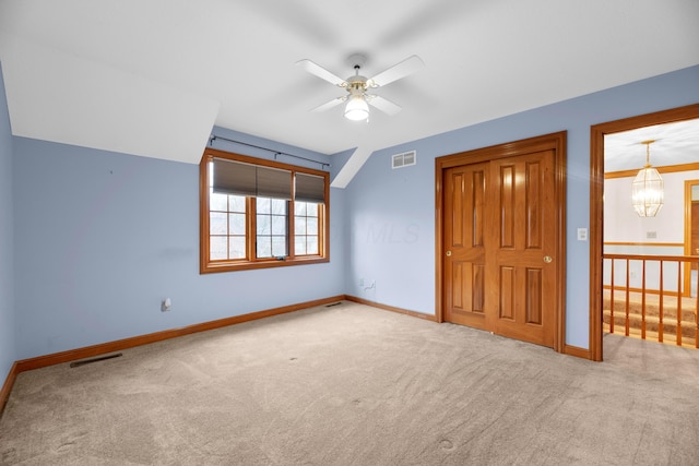 unfurnished bedroom with light colored carpet and ceiling fan with notable chandelier