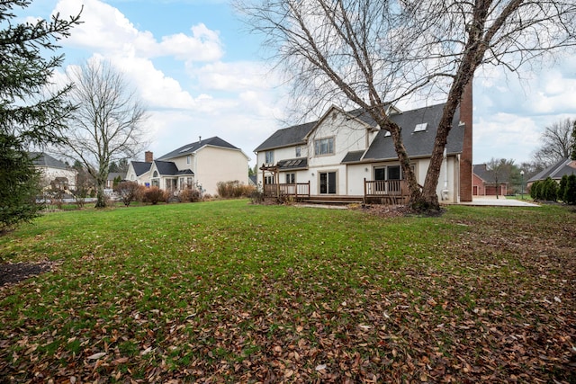 rear view of house featuring a yard and a wooden deck