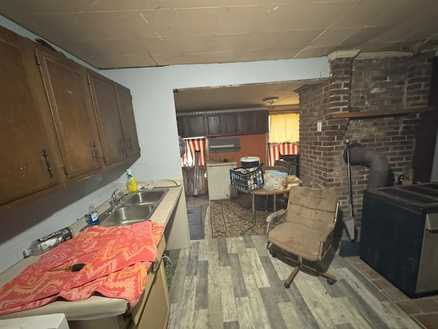 kitchen featuring light hardwood / wood-style floors, dark brown cabinetry, sink, and a wood stove