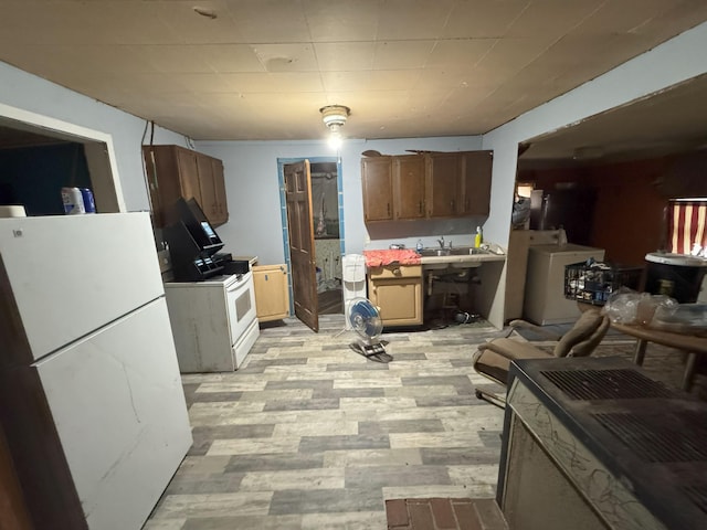 kitchen featuring washer / dryer, white appliances, light hardwood / wood-style floors, and sink