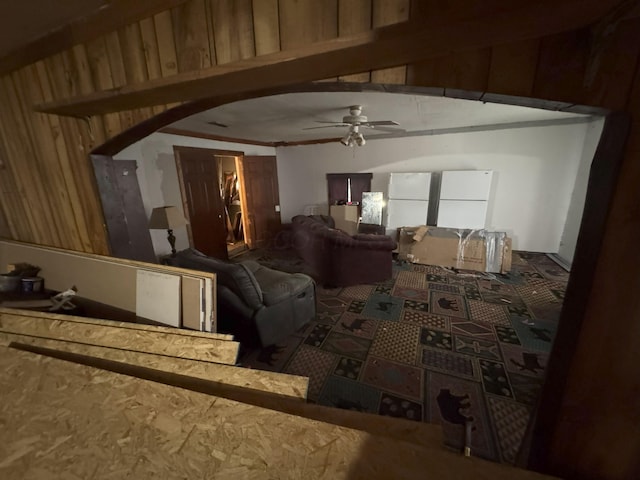 interior space featuring ceiling fan and wood walls