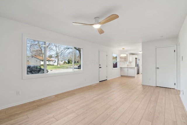 unfurnished living room featuring ceiling fan and light hardwood / wood-style floors