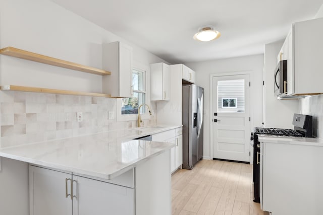 kitchen featuring sink, tasteful backsplash, kitchen peninsula, stainless steel appliances, and white cabinets