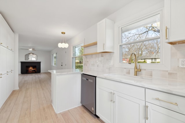 kitchen with white cabinetry, dishwasher, sink, hanging light fixtures, and light hardwood / wood-style floors