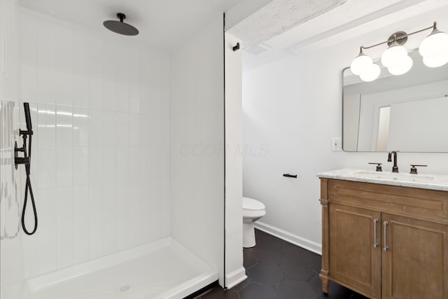 bathroom with tiled shower, tile patterned floors, toilet, and vanity