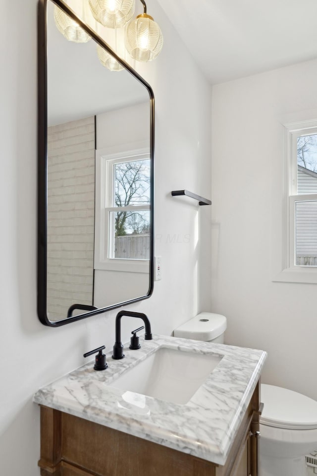 bathroom with vanity, toilet, and a healthy amount of sunlight