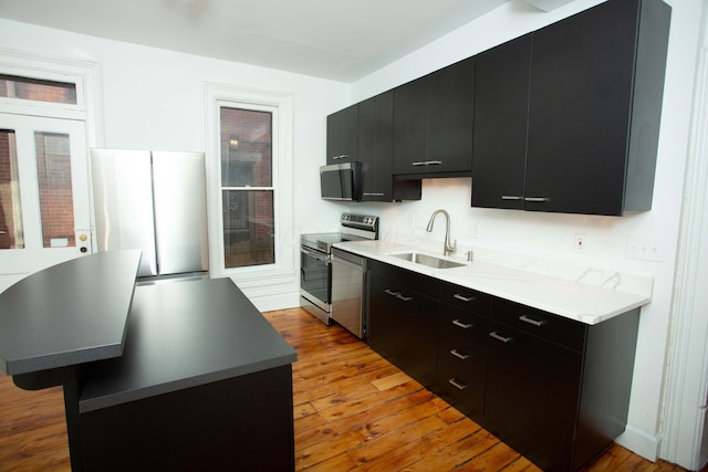 kitchen with sink, a center island, light hardwood / wood-style flooring, a breakfast bar, and appliances with stainless steel finishes