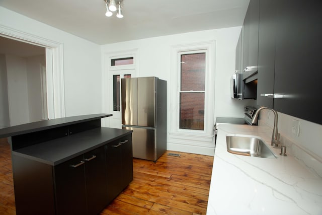 kitchen with stainless steel fridge, stove, sink, light hardwood / wood-style floors, and a breakfast bar area