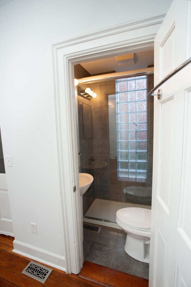 bathroom featuring toilet and a shower with door