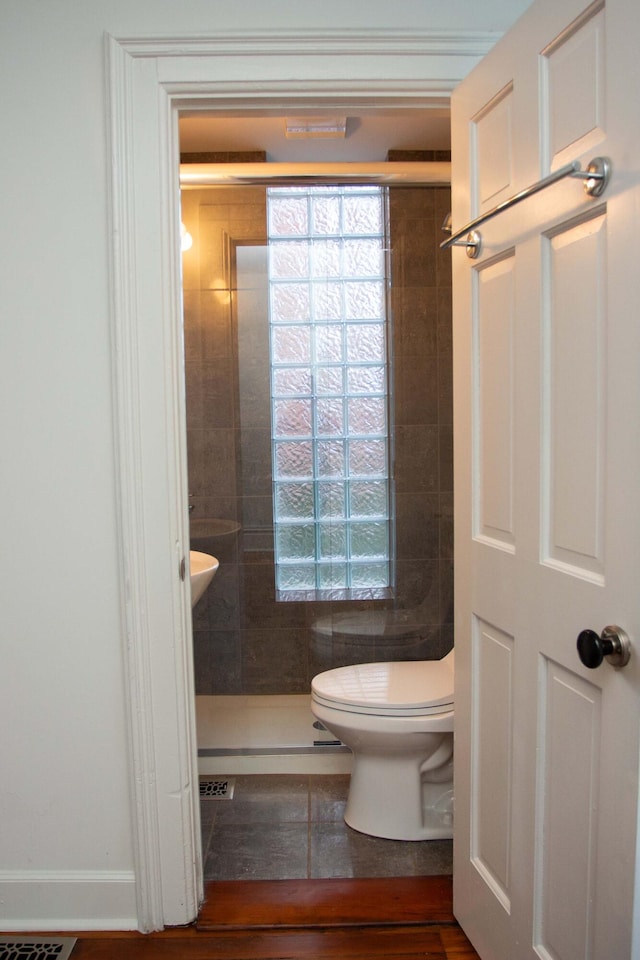 bathroom featuring a tile shower and toilet