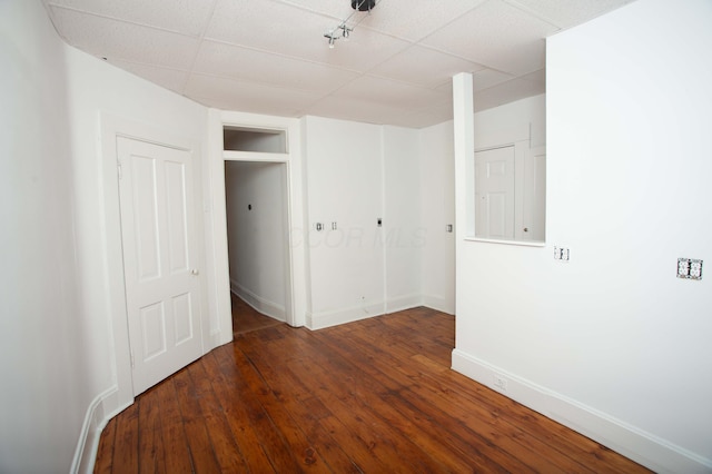 unfurnished bedroom featuring a paneled ceiling and dark hardwood / wood-style floors