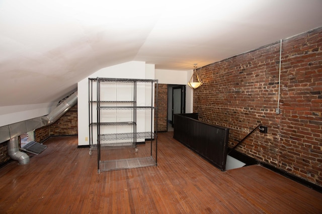 bonus room featuring lofted ceiling, brick wall, and dark hardwood / wood-style floors