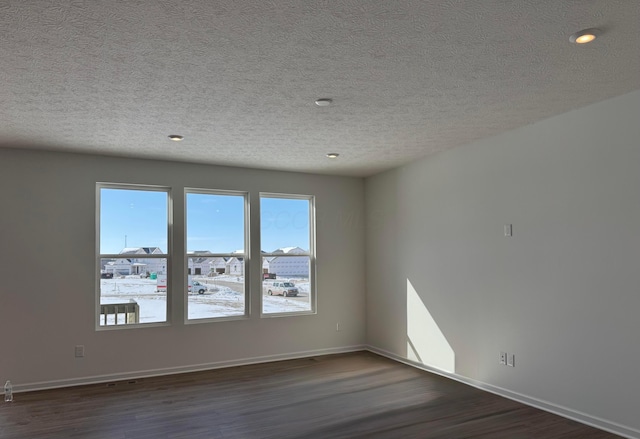 empty room with dark hardwood / wood-style flooring and a textured ceiling