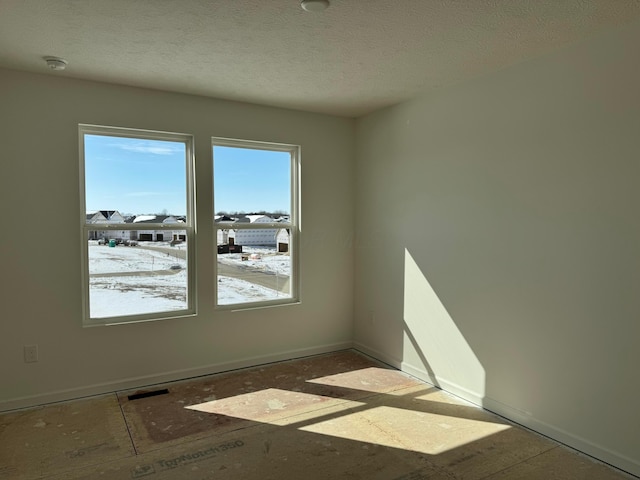 unfurnished room with a textured ceiling