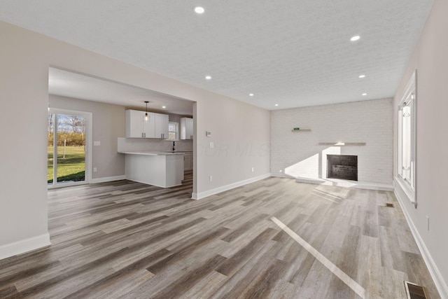 unfurnished living room with a fireplace, light hardwood / wood-style flooring, and a textured ceiling