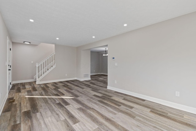 unfurnished room featuring an inviting chandelier and hardwood / wood-style floors