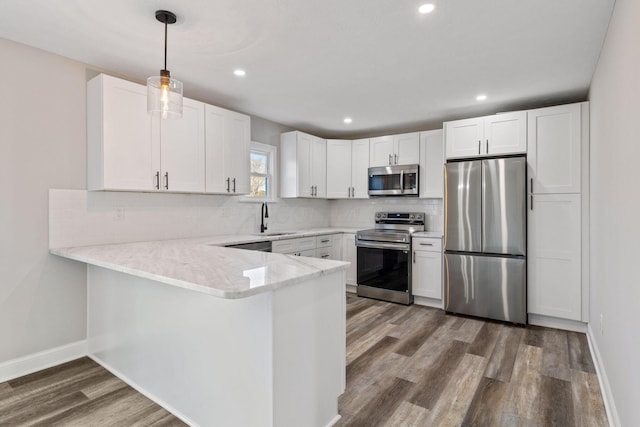 kitchen with sink, hanging light fixtures, kitchen peninsula, stainless steel appliances, and white cabinets