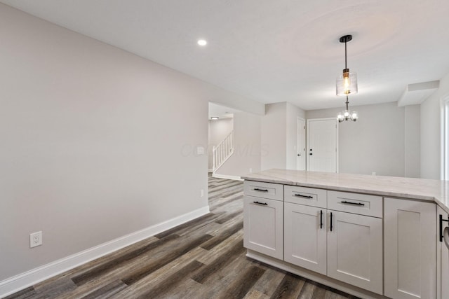 kitchen featuring white cabinetry, an inviting chandelier, light stone countertops, dark hardwood / wood-style flooring, and decorative light fixtures